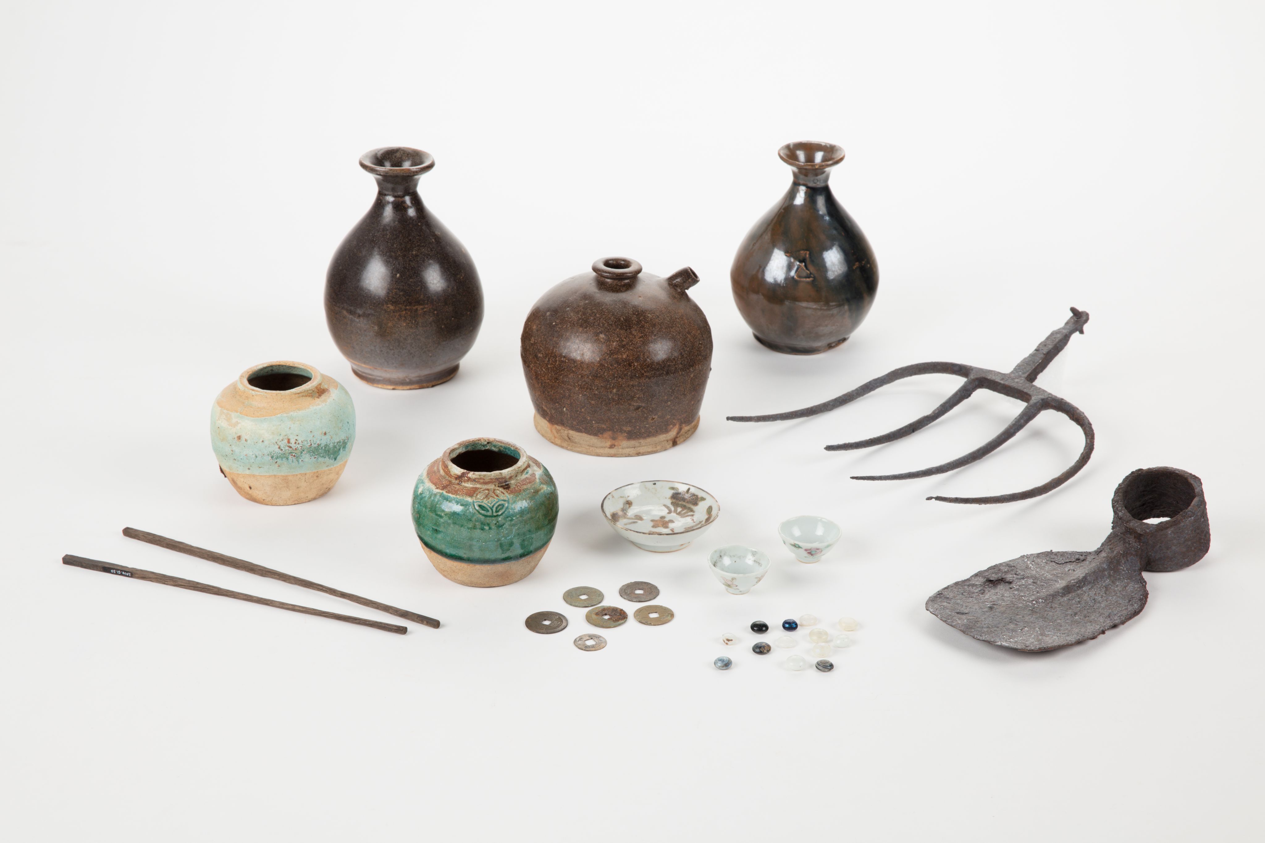 The image shows a white surface with a variety of vases, tools, and other objects arranged on top of it. The vases are of different sizes and shapes, and the tools appear to be of various sizes and colours