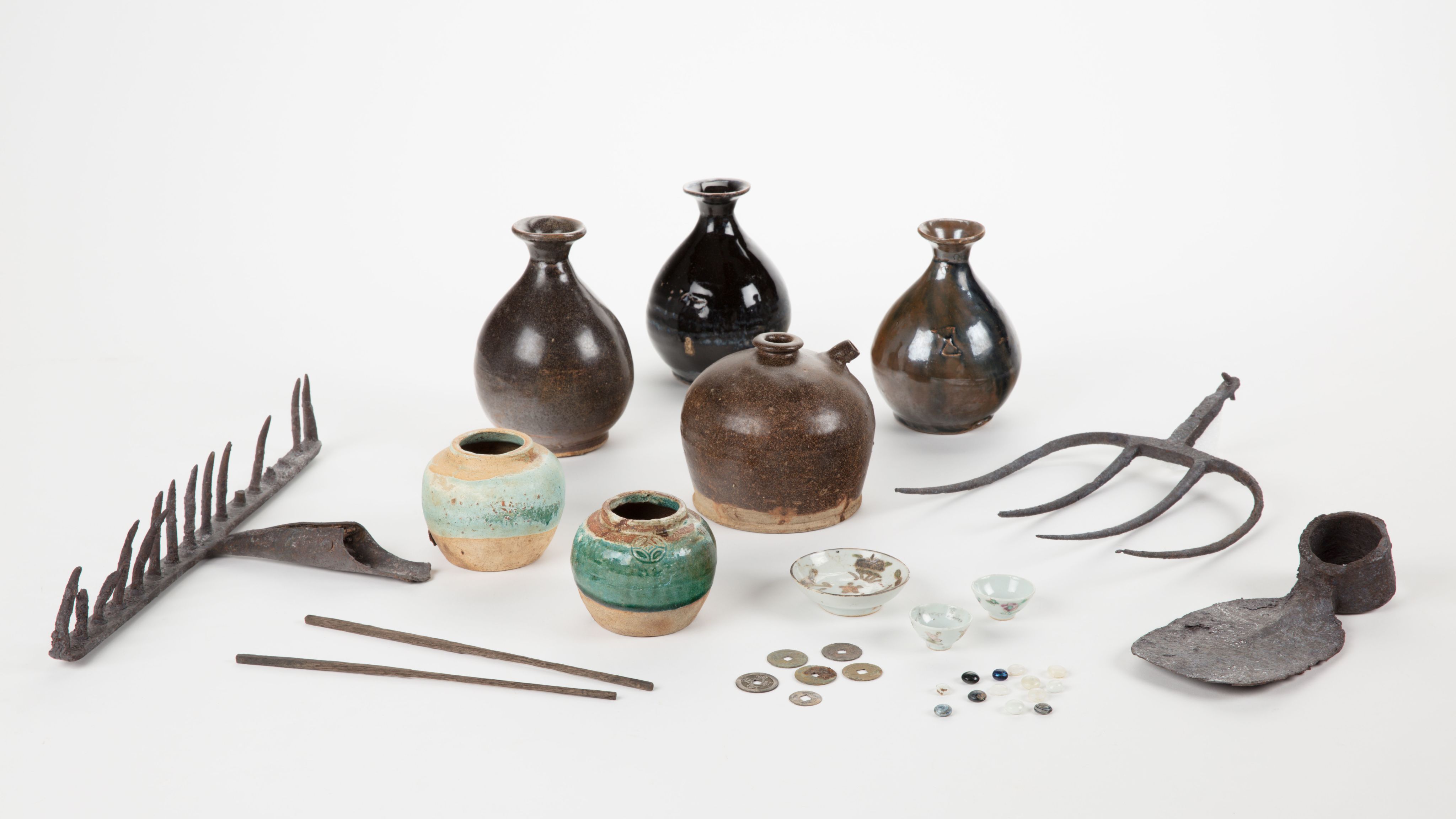 The image shows a white surface with a variety of vases, tools, and other objects arranged on top of it. The vases are of different sizes and shapes, and the tools appear to be of various sizes and colours.