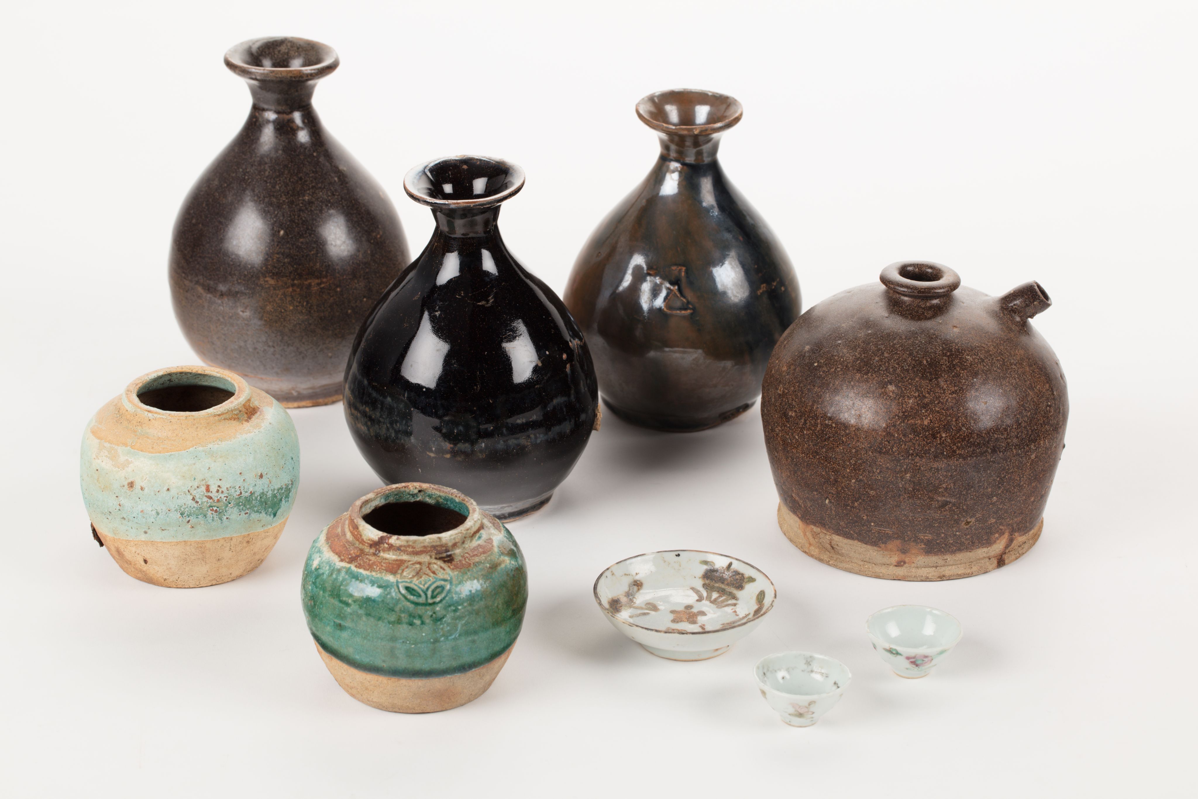 The image shows a white surface with a variety of vases, tools, and other objects arranged on top of it. The vases are of different sizes and shapes, and the tools appear to be of various sizes and colours