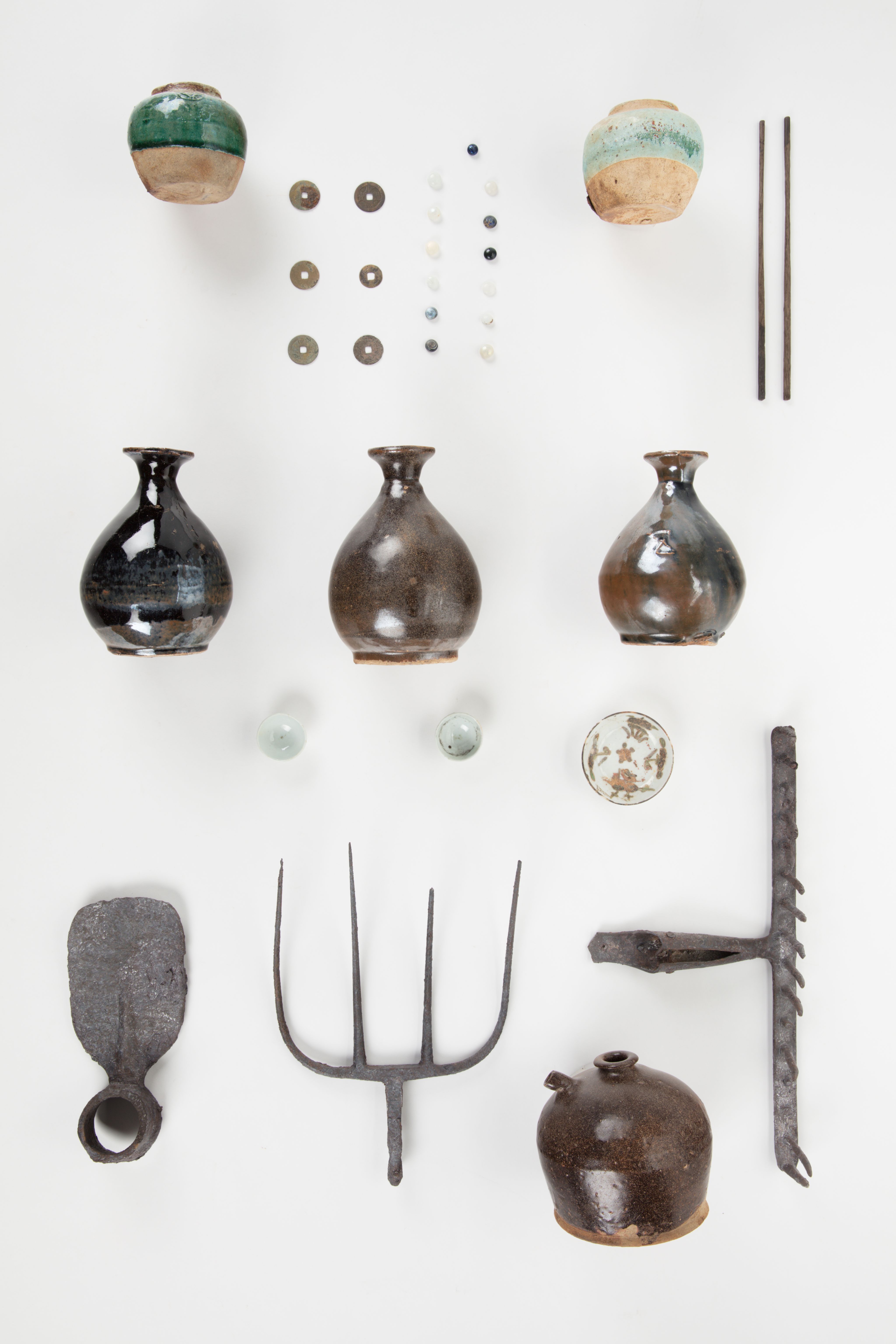 The image shows a white surface with a variety of vases, tools, and other objects arranged on top of it. The vases are of different sizes and shapes, and the tools appear to be of various sizes and colours