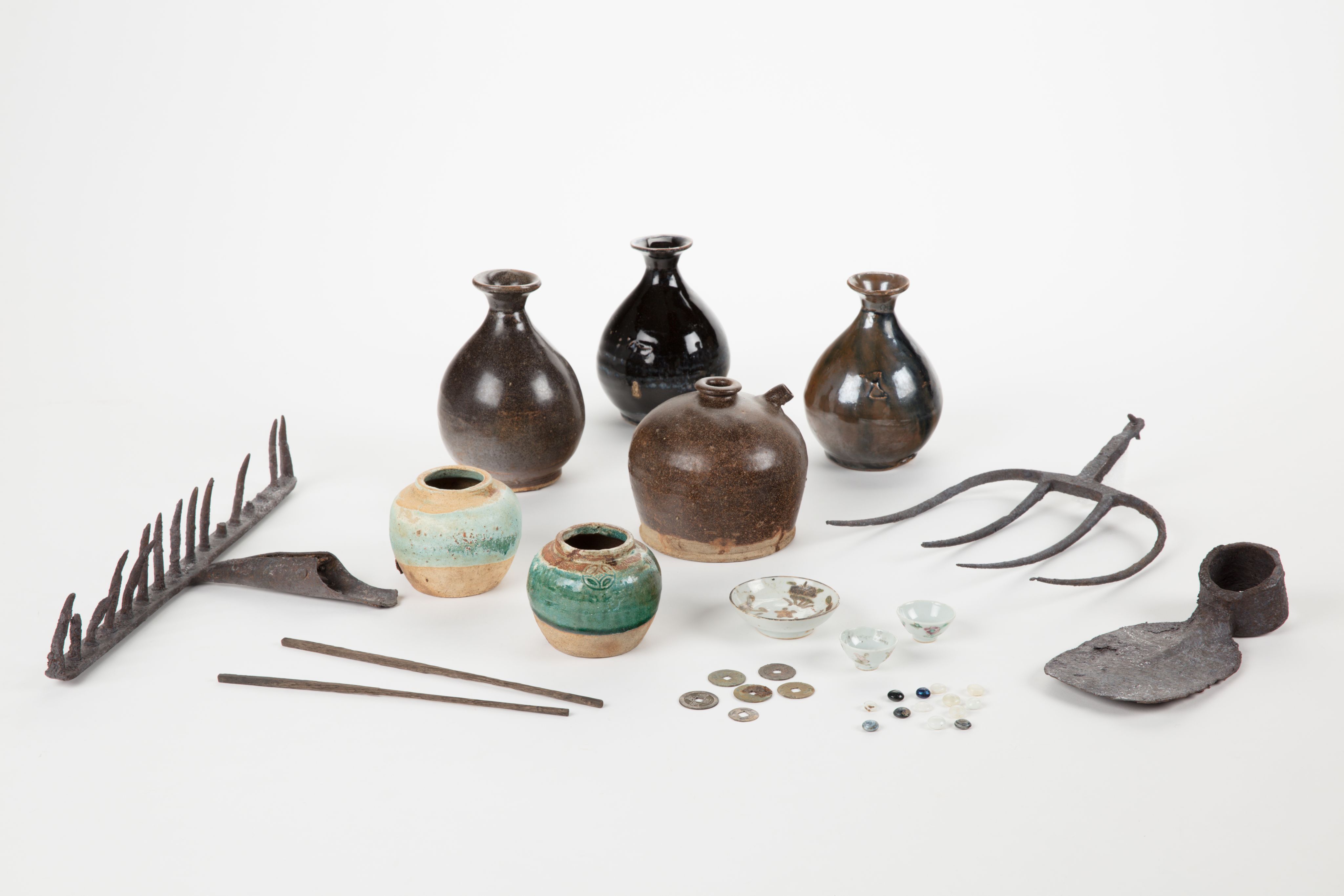 The image shows a white surface with a variety of vases, tools, and other objects arranged on top of it. The vases are of different sizes and shapes, and the tools appear to be of various sizes and colours