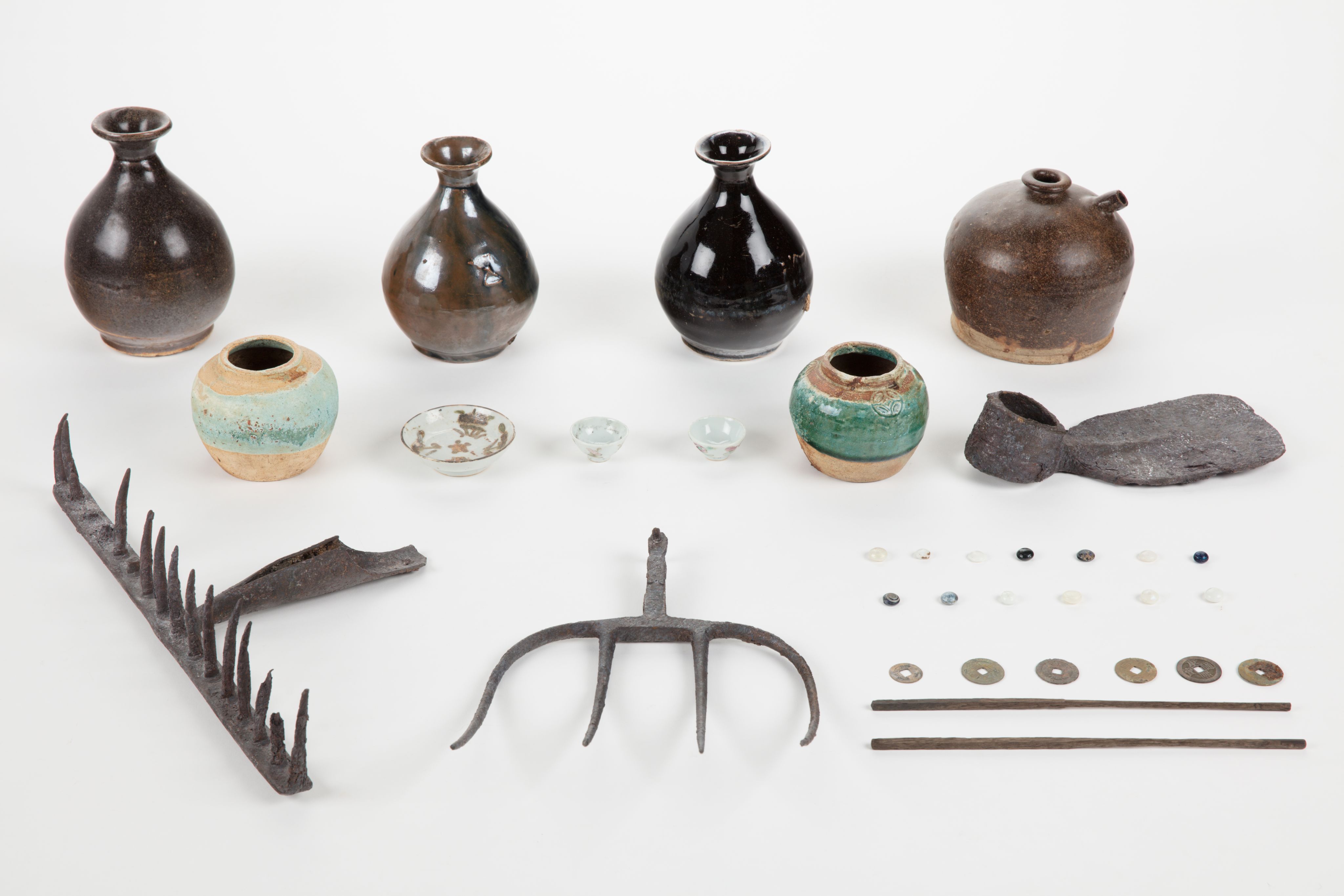 The image shows a white surface with a variety of vases, tools, and other objects arranged on top of it. The vases are of different sizes and shapes, and the tools appear to be of various sizes and colours