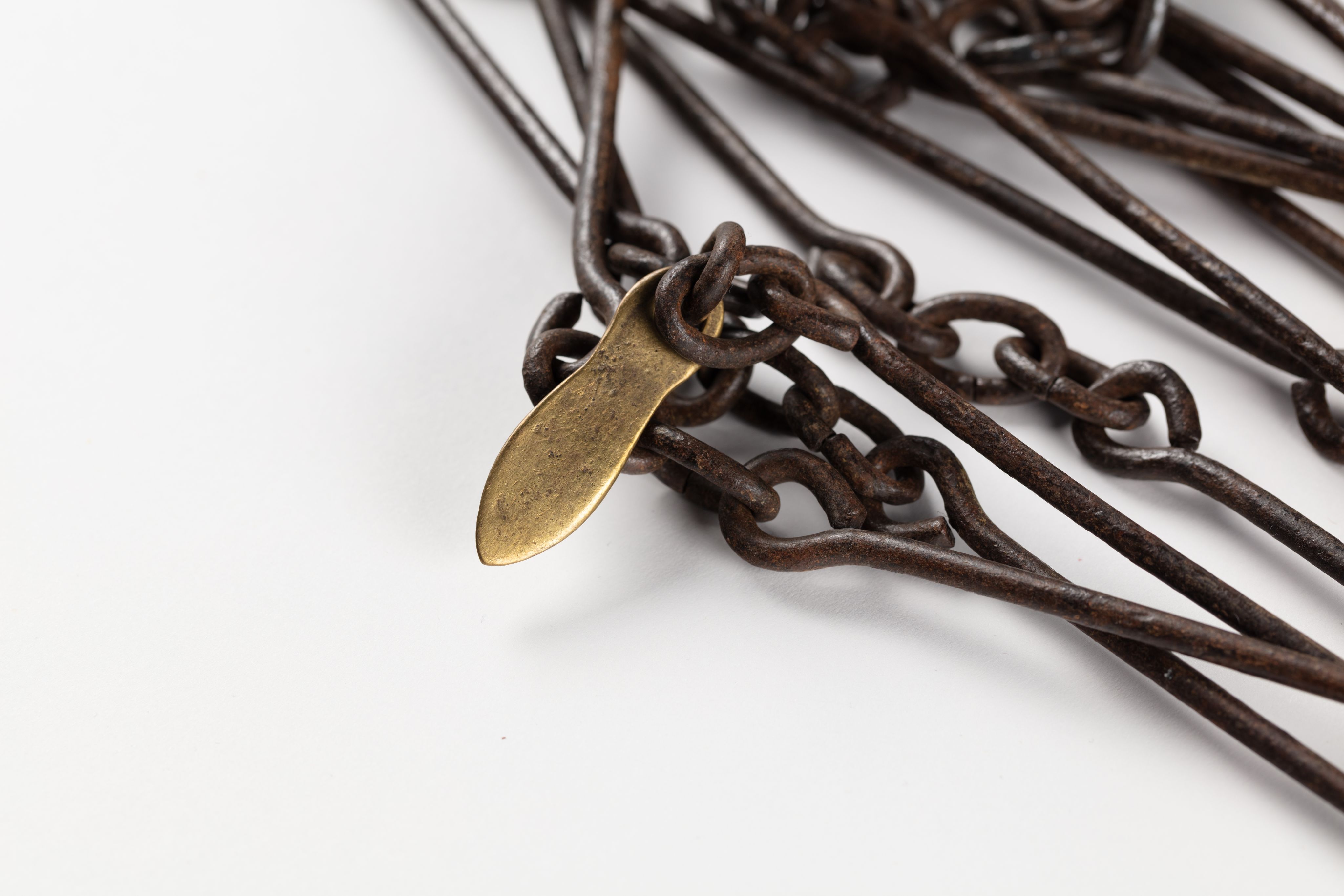 Surveyor's chain made from equally spaced steel links with brass markers in the form of one, two, three and four 'fingers'.