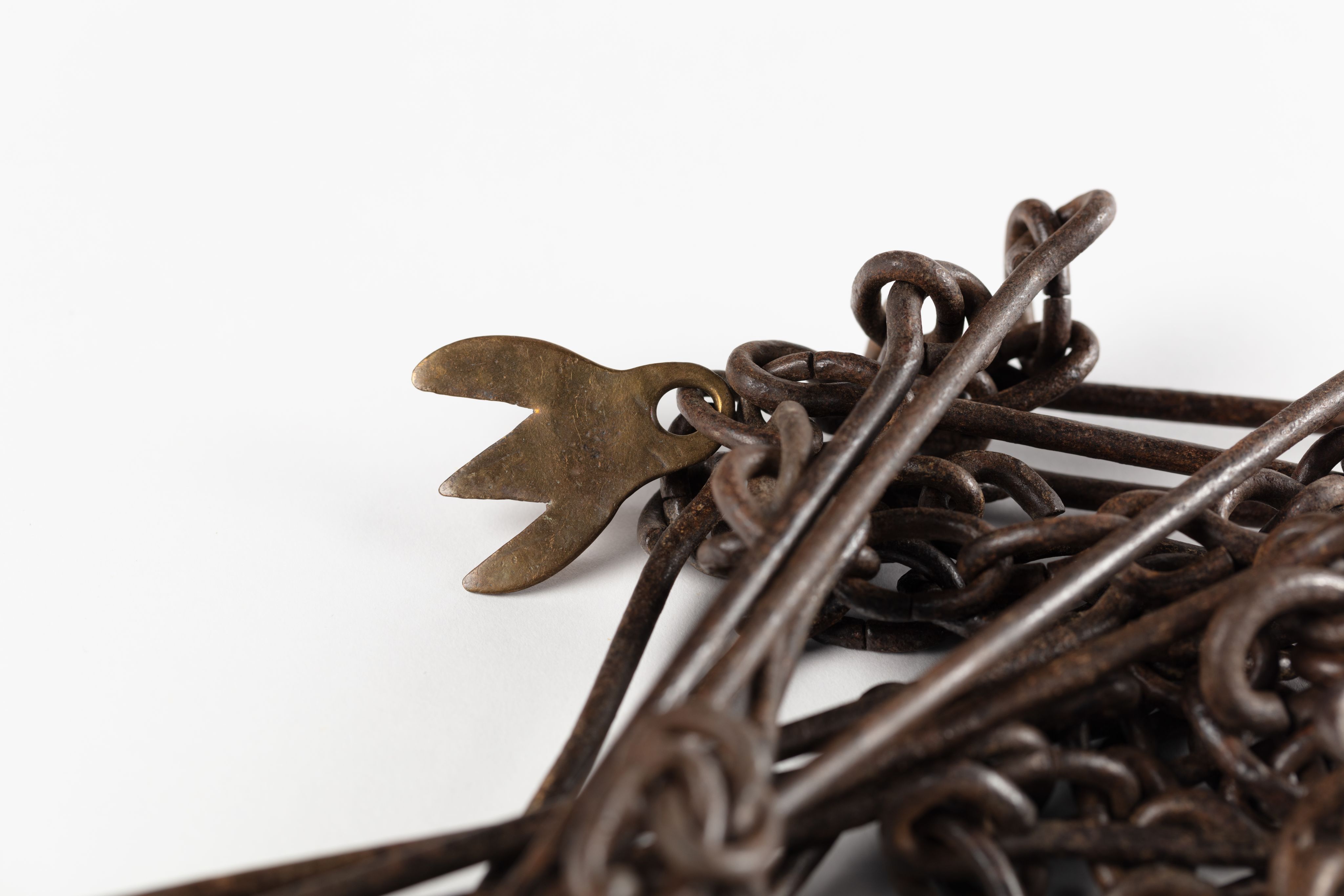 Surveyor's chain made from equally spaced steel links with brass markers in the form of one, two, three and four 'fingers'.