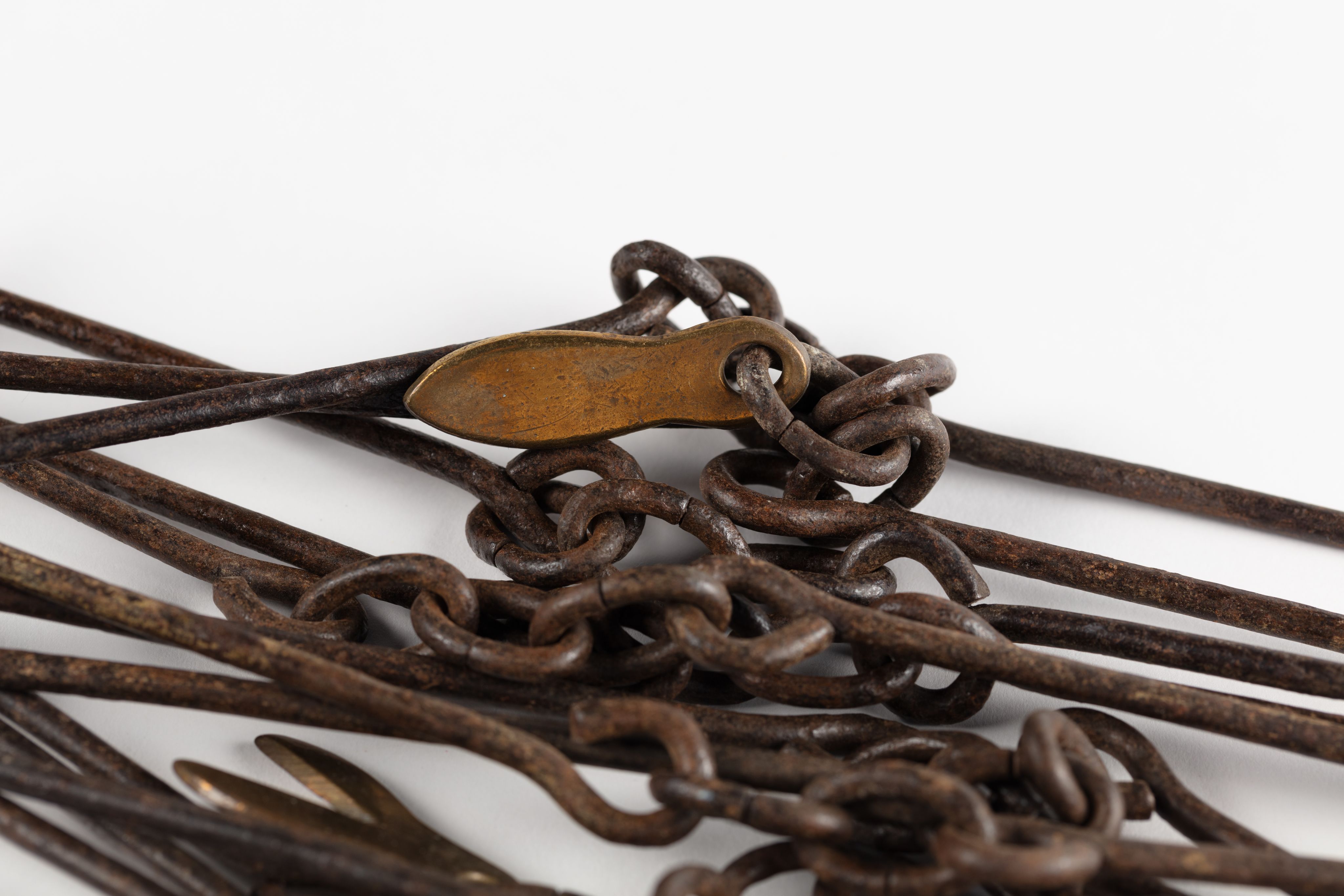Surveyor's chain made from equally spaced steel links with brass markers in the form of one, two, three and four 'fingers'.