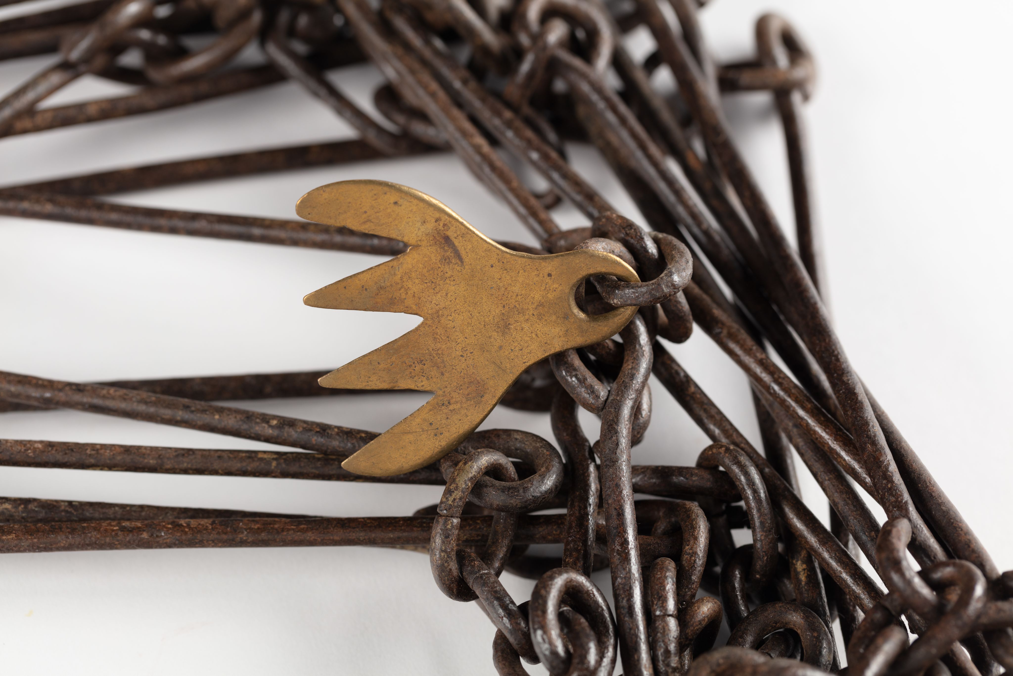 Surveyor's chain made from equally spaced steel links with brass markers in the form of one, two, three and four 'fingers'.