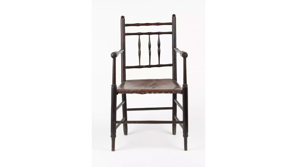 Colonial-style armchair made from dark wood with a deep reddish brown leather set.