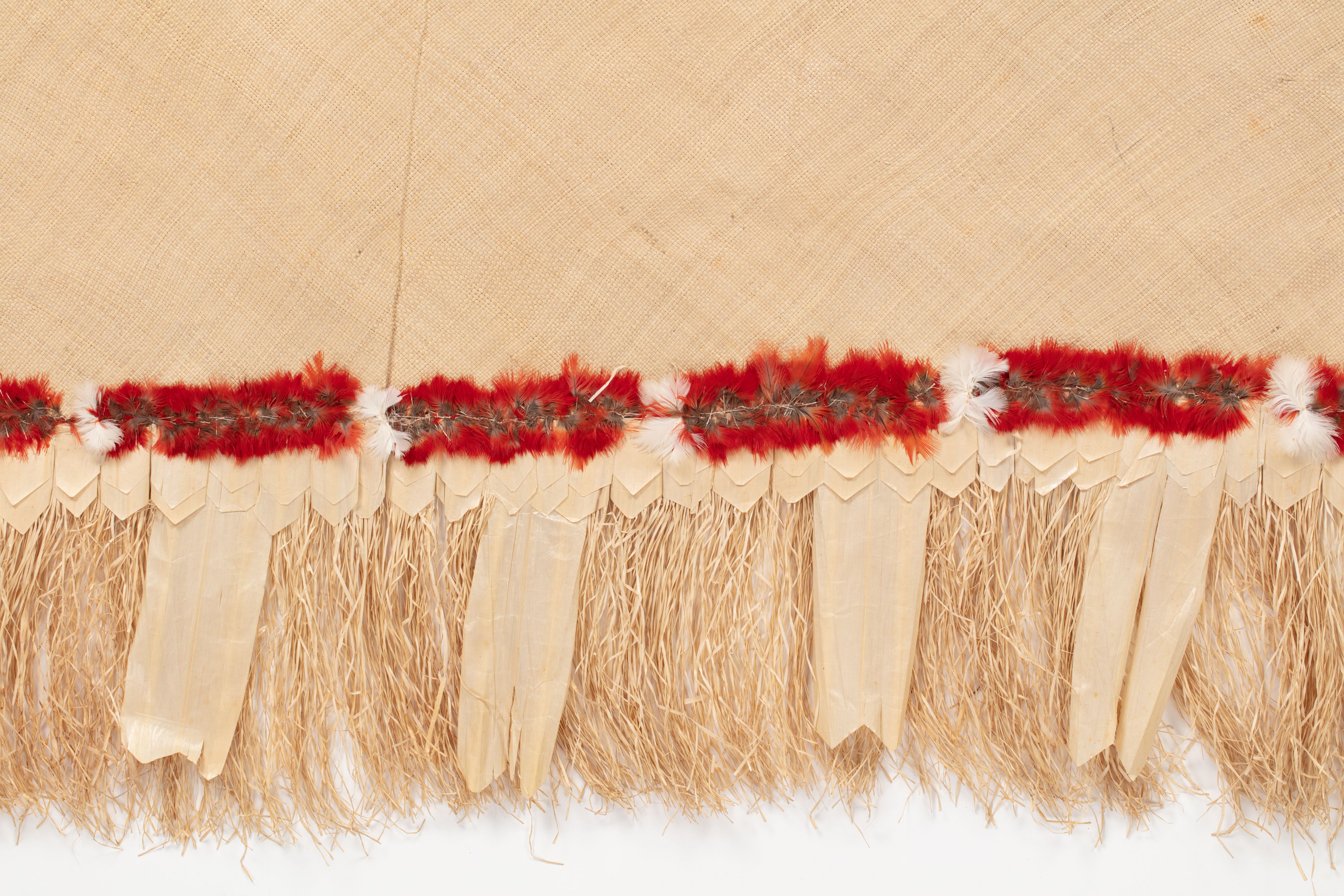 Fine mat made from pandanus (leaf) with "X MULI X OAIGA X" written the edge in ink. Red feathers are featured along the border of mat.
