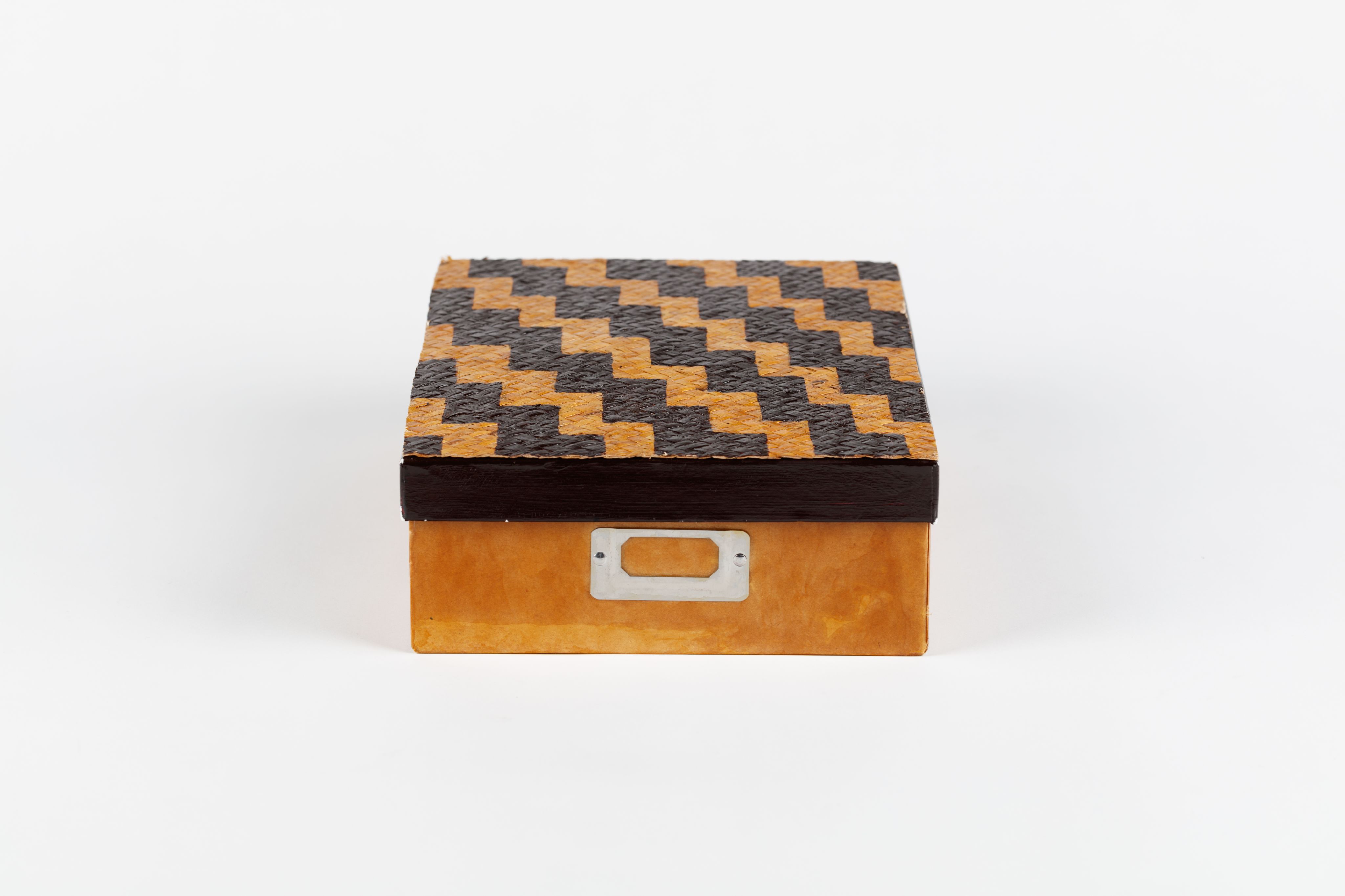 Alt text: cardboard box with woven lid decorated with poutama (stairway) design 