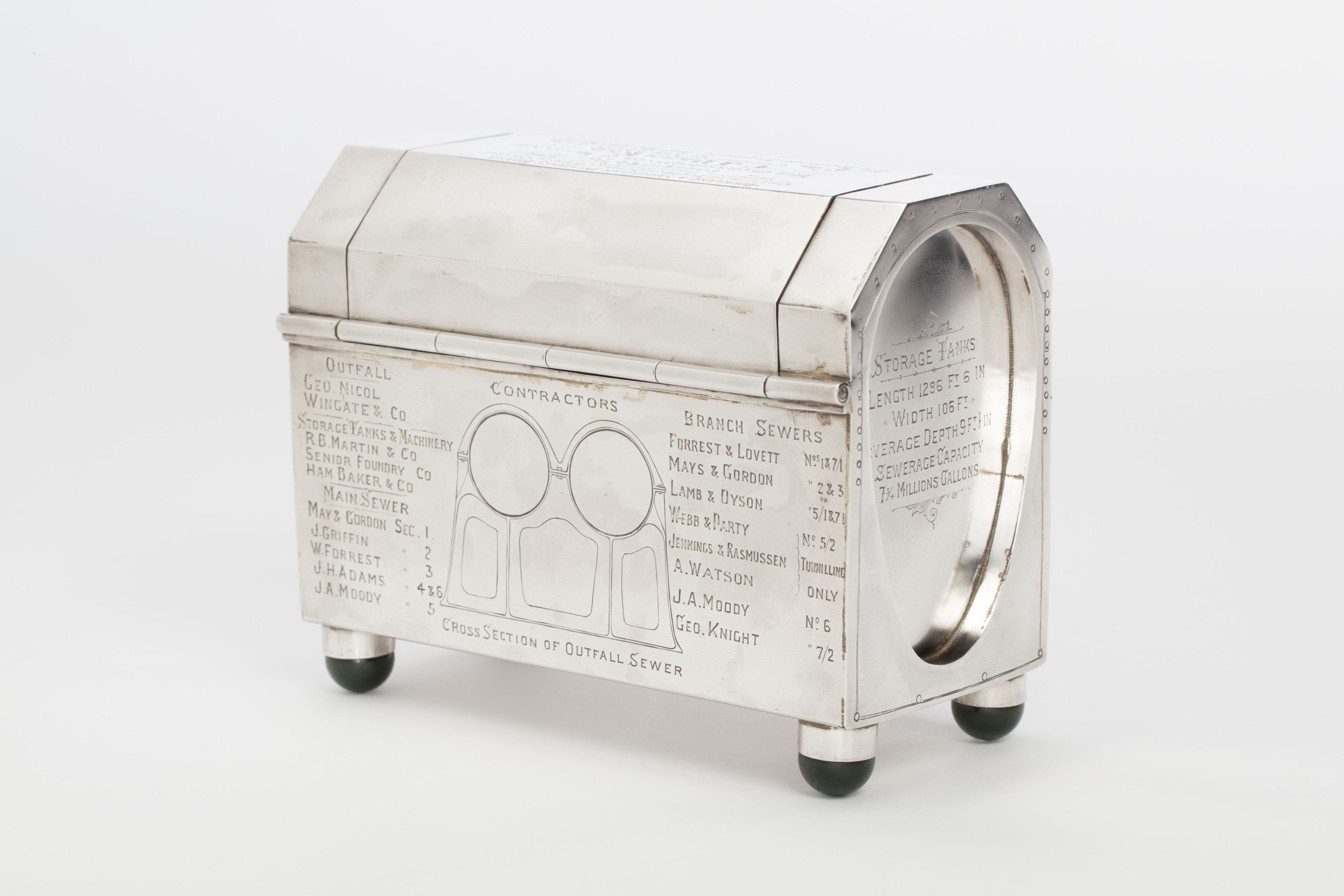 Finely crafted silver box (or casket) designed in the shape of the main sewage pipe, engraved with the names of the members of the drainage board along with technical sewage . On one side there is an engraved illustration of Ōkahu Bay, showing the Ngāti Whātua Ōrākei papakāinga and the newly installed sewer pipe running along the foreshore in front of it.