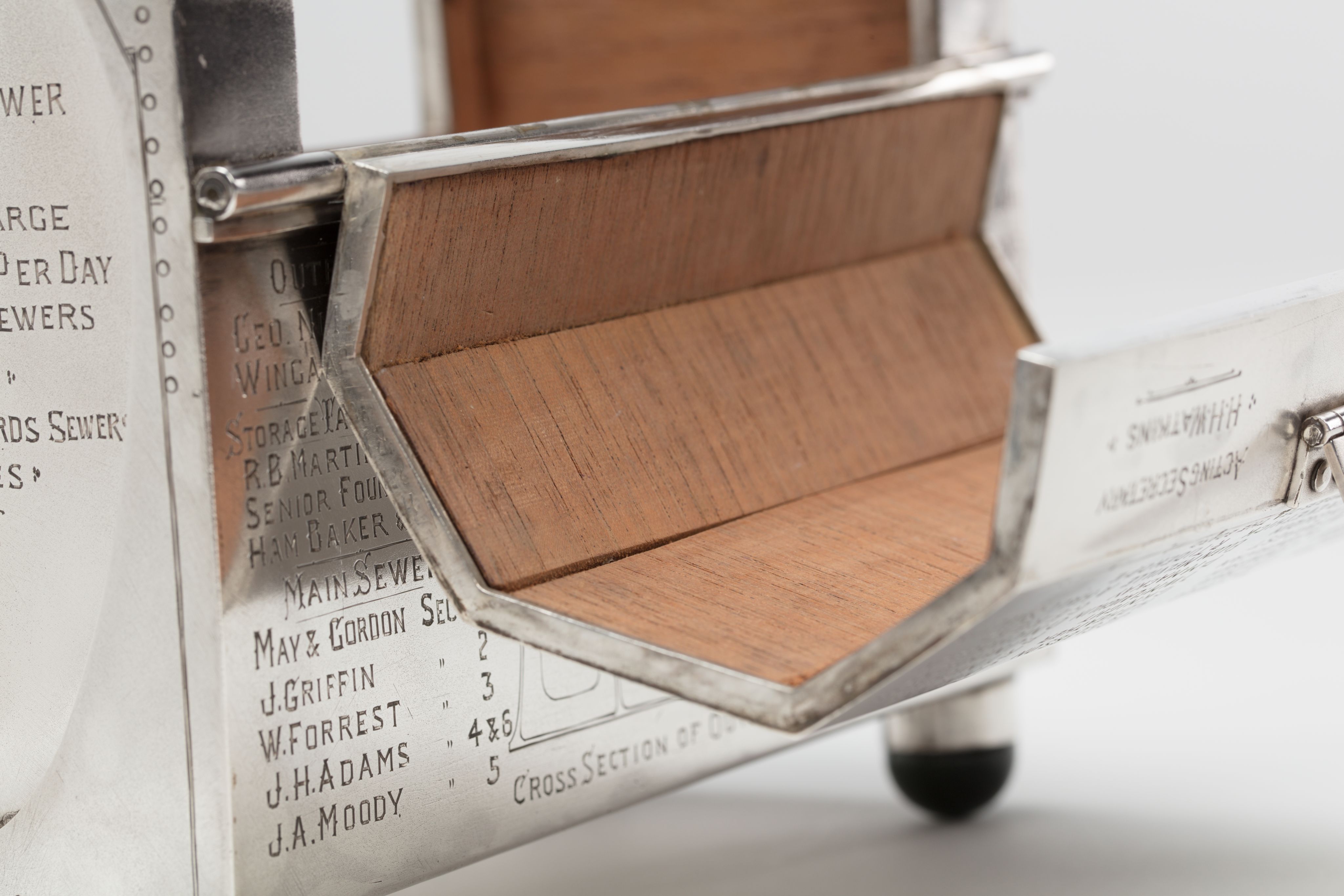 Finely crafted silver box (or casket) designed in the shape of the main sewage pipe, engraved with the names of the members of the drainage board along with technical sewage . On one side there is an engraved illustration of Ōkahu Bay, showing the Ngāti Whātua Ōrākei papakāinga and the newly installed sewer pipe running along the foreshore in front of it.