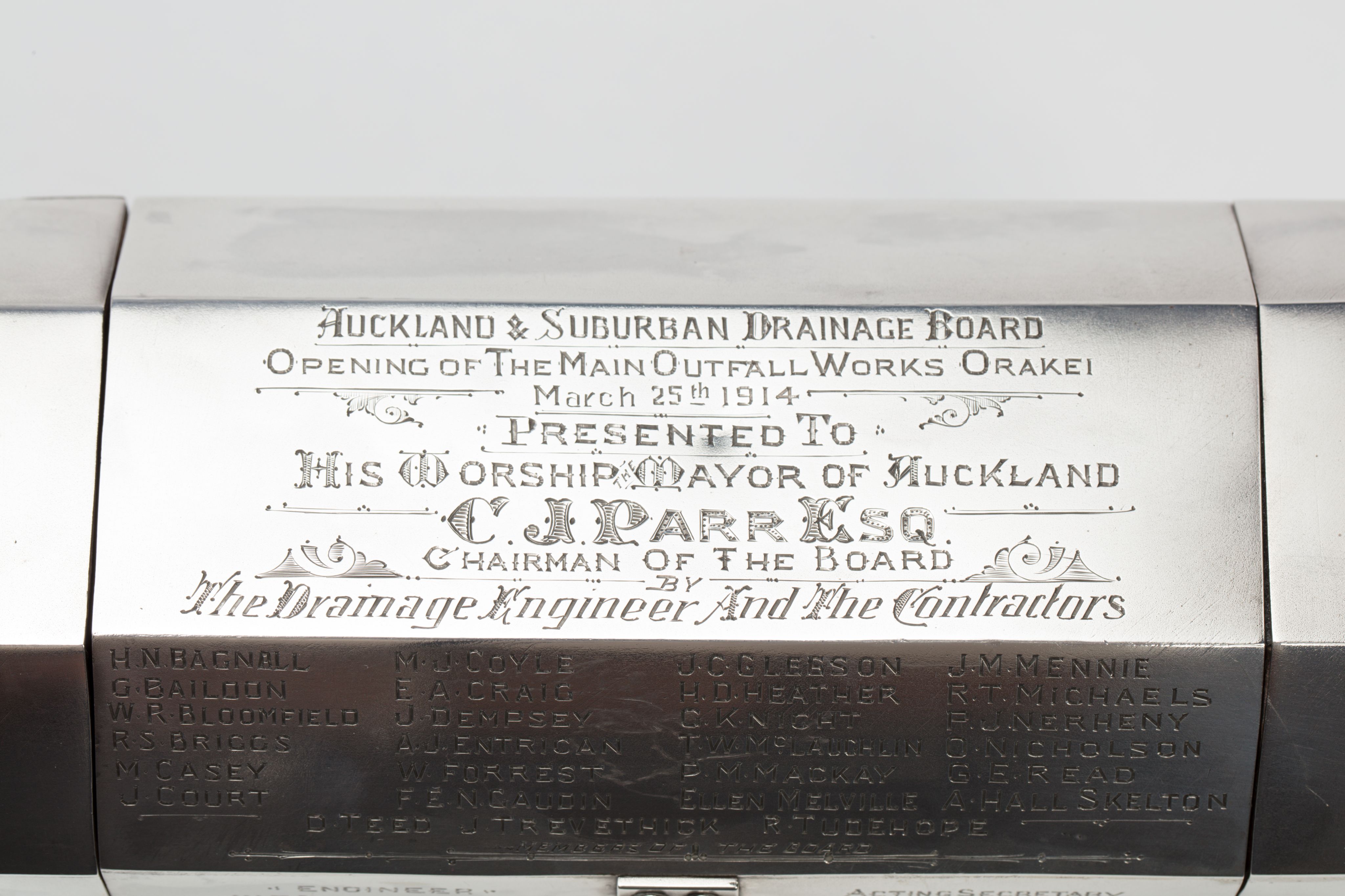 Finely crafted silver box (or casket) designed in the shape of the main sewage pipe, engraved with the names of the members of the drainage board along with technical sewage . On one side there is an engraved illustration of Ōkahu Bay, showing the Ngāti Whātua Ōrākei papakāinga and the newly installed sewer pipe running along the foreshore in front of it.