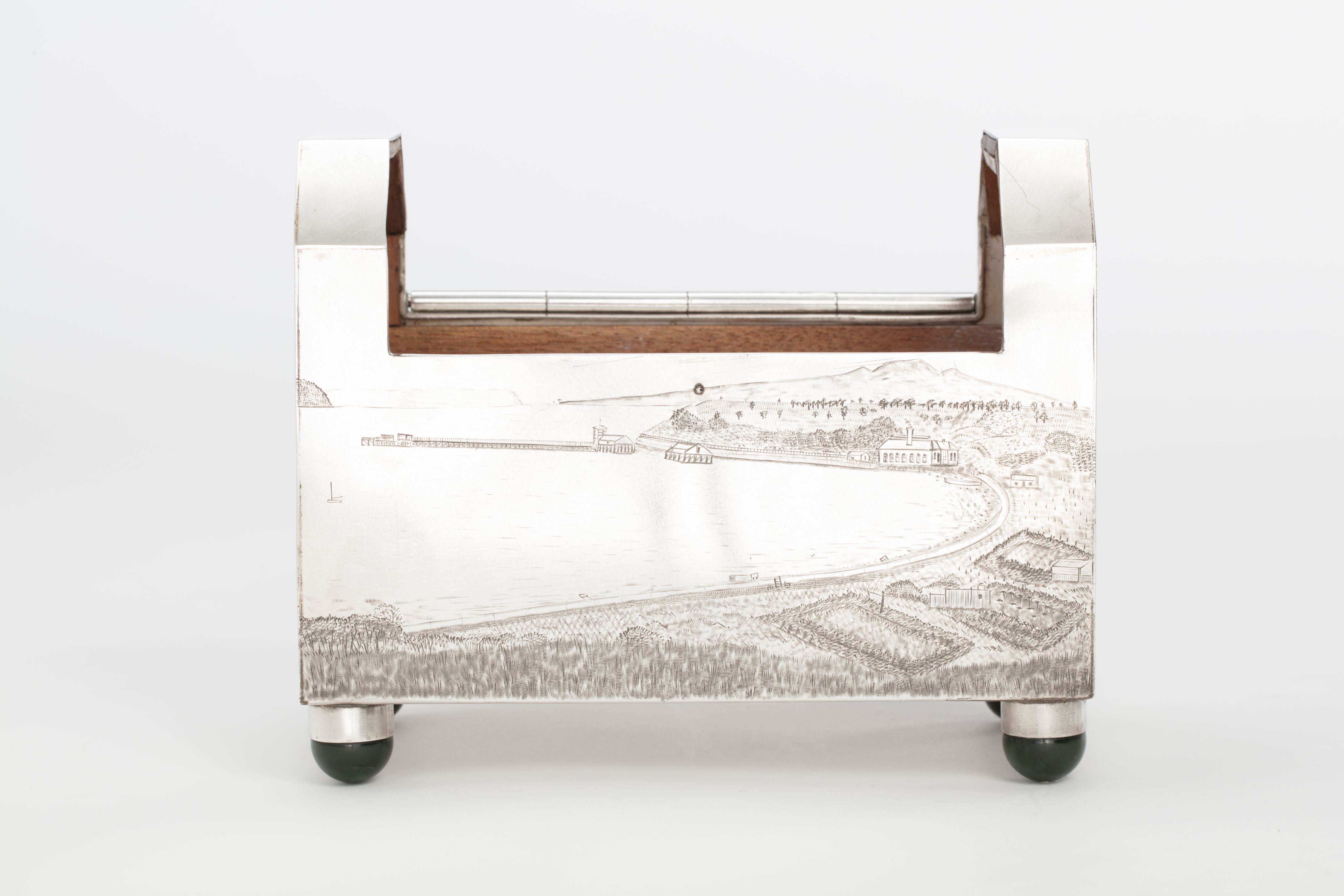 Finely crafted silver box (or casket) designed in the shape of the main sewage pipe, engraved with the names of the members of the drainage board along with technical sewage . On one side there is an engraved illustration of Ōkahu Bay, showing the Ngāti Whātua Ōrākei papakāinga and the newly installed sewer pipe running along the foreshore in front of it.