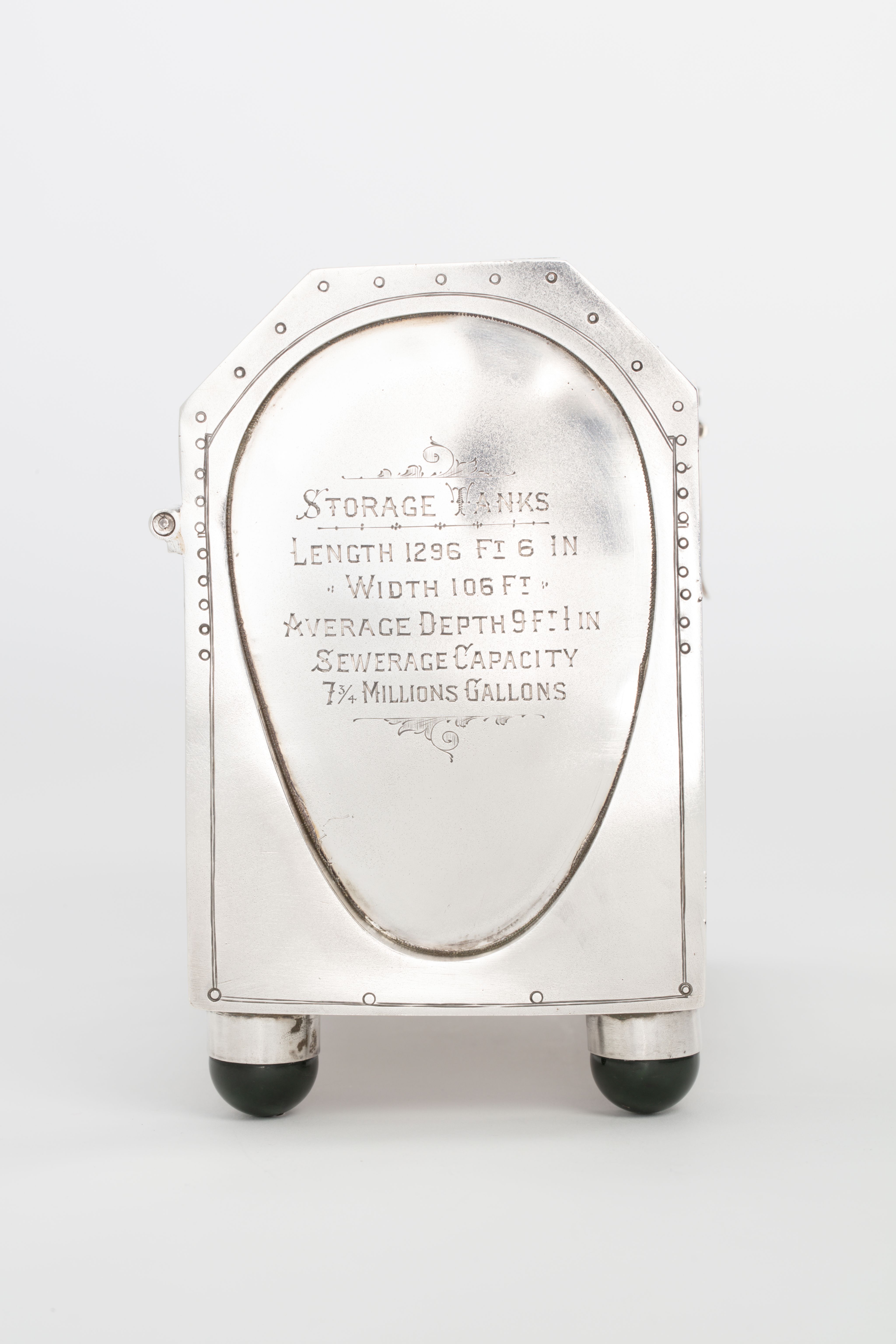 Finely crafted silver box (or casket) designed in the shape of the main sewage pipe, engraved with the names of the members of the drainage board along with technical sewage . On one side there is an engraved illustration of Ōkahu Bay, showing the Ngāti Whātua Ōrākei papakāinga and the newly installed sewer pipe running along the foreshore in front of it.