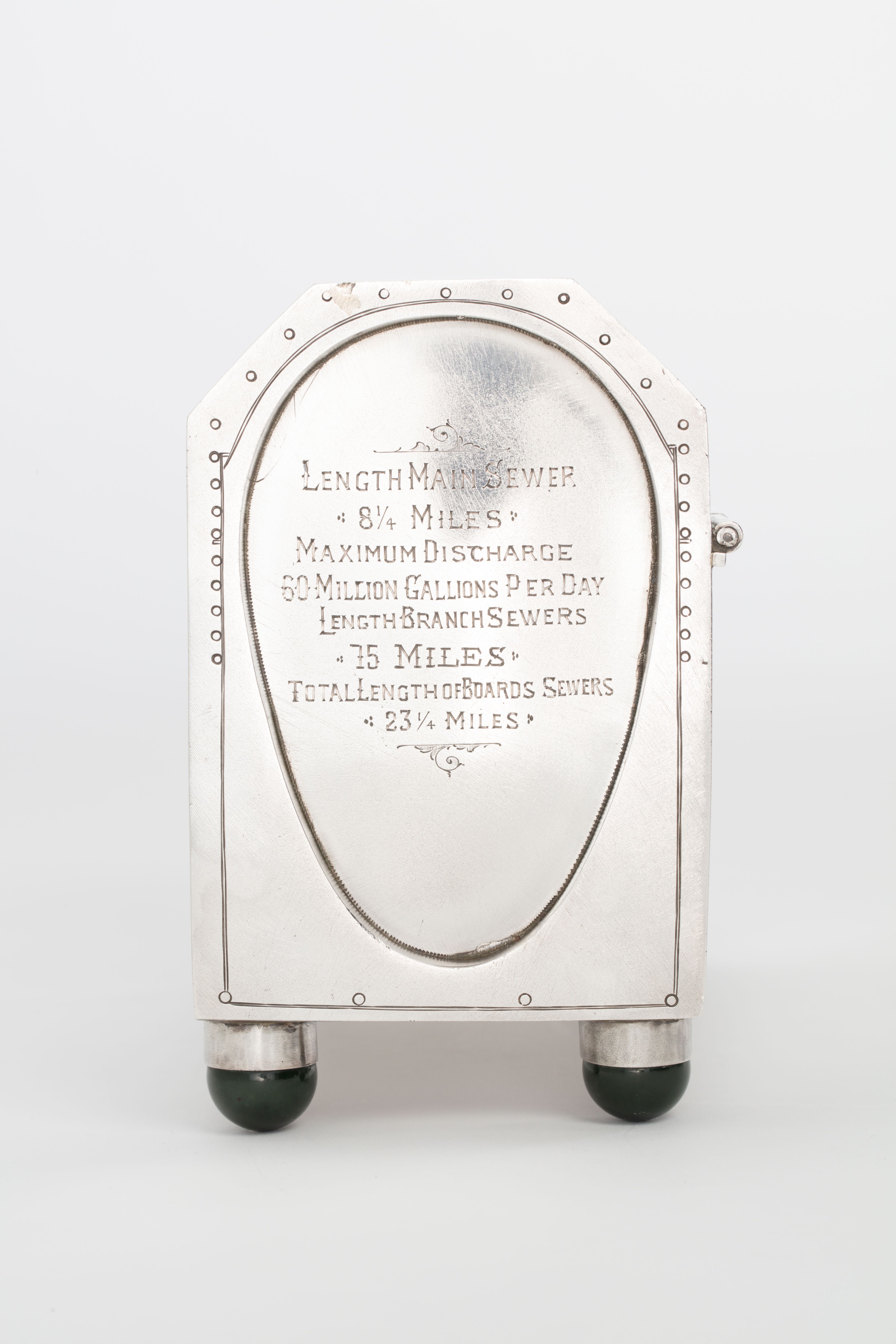 Finely crafted silver box (or casket) designed in the shape of the main sewage pipe, engraved with the names of the members of the drainage board along with technical sewage . On one side there is an engraved illustration of Ōkahu Bay, showing the Ngāti Whātua Ōrākei papakāinga and the newly installed sewer pipe running along the foreshore in front of it.